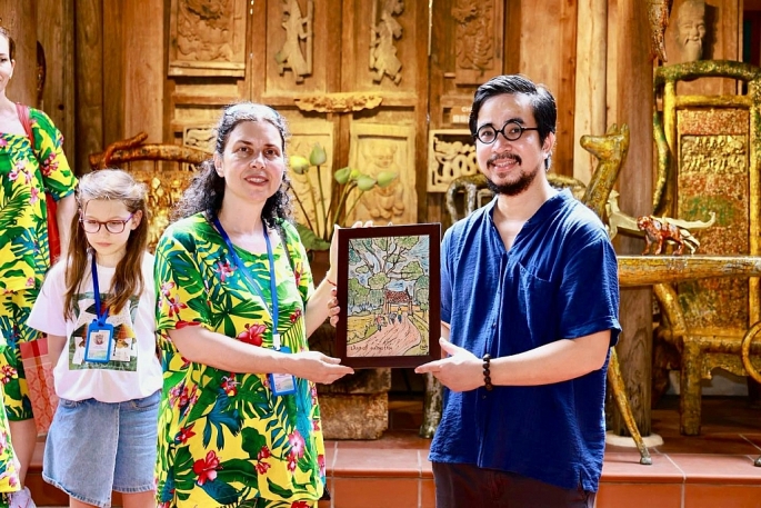 Nghệ nhân trẻ Nguyễn Tấn Phát trao tặng món quà tranh in khắc gỗ cho du khách quốc tế. Ảnh: NVCC