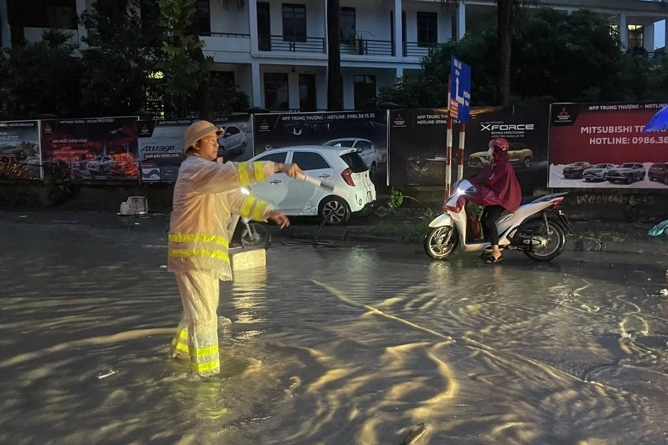 Cảnh sát giao thông dầm mưa giúp đỡ người dân di chuyển qua các điểm úng ngập