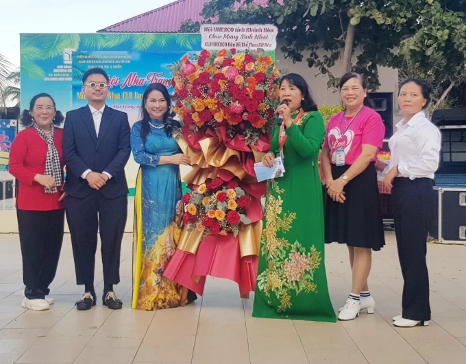 Bà Thanh Hương (áo dài xanh, bên trái)- Chủ tịch Hội UNESCO Khánh Hòa tặng hoa chúc mừng