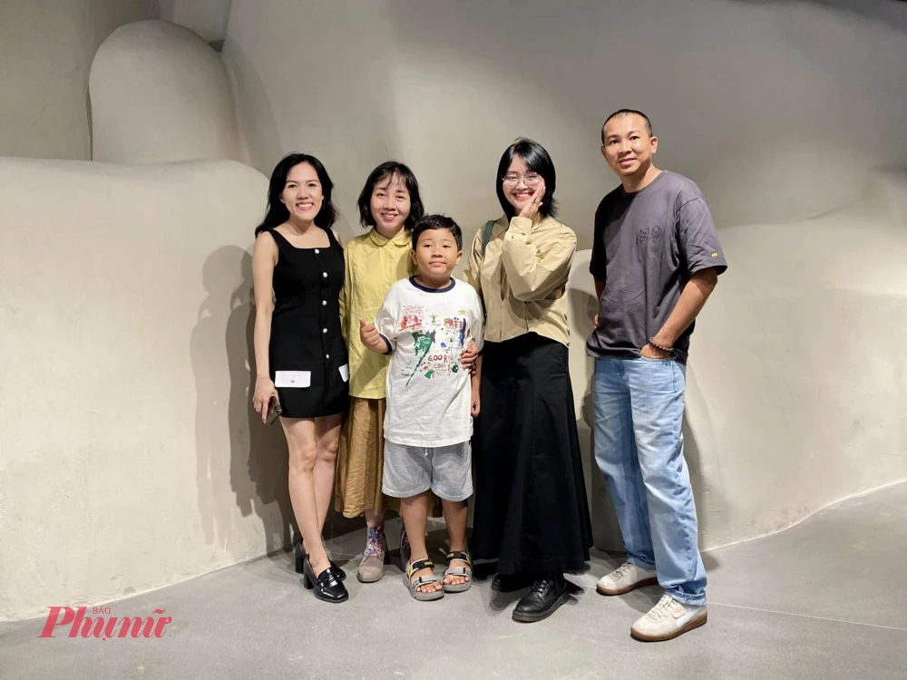 Họa sĩ Trần Hạnh (thứ hai từ phải qua) chụp ảnh lưu niệm cùng người thân tại triển lãm. Ảnh: NVCC