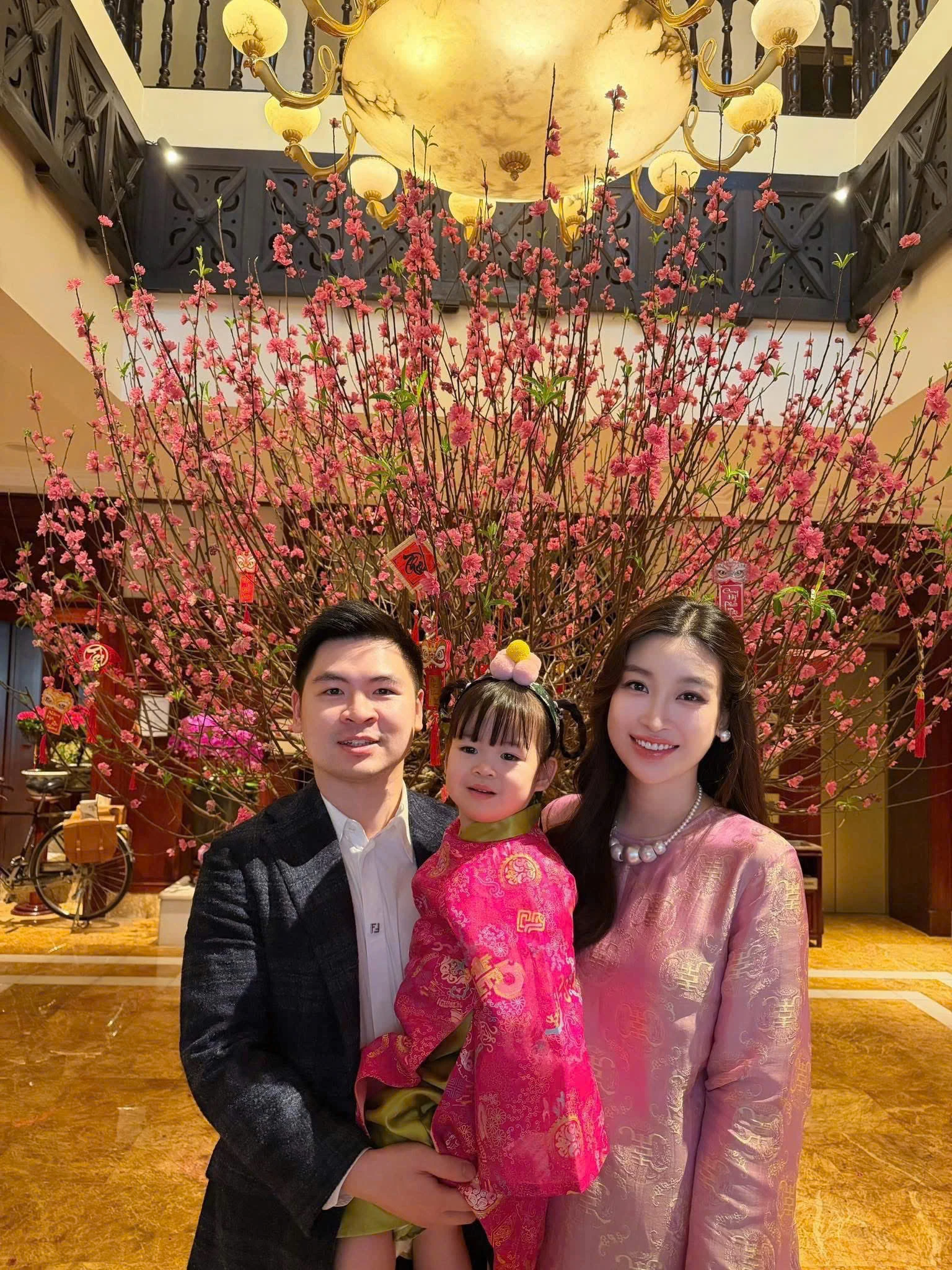 Con gái hoa hậu Đỗ Mỹ Linh gây thiện cảm với phong cách truyền thống ngọt ngào. Cô bé diện bộ áo dài gấm hồng cánh sen nổi bật, điểm họa tiết vàng ánh kim mang ý nghĩa may mắn và phúc lộc đầu năm. Phom dáng rộng rãi, chất liệu gấm mềm giúp trang phục vừa giữ được nét lễ nghi, vừa đảm bảo sự thoải mái cho trẻ nhỏ.